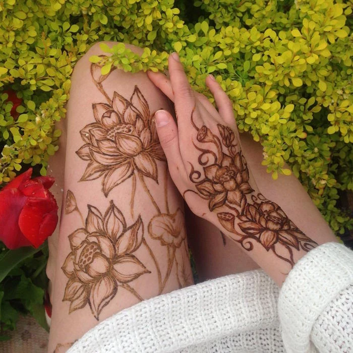 lotuses painted with brown henna, on the thigh and hand of a woman, dressed in a knitted white dress