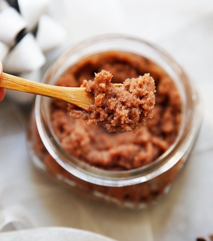 body scrub made with sugar and cocoa powder, inside a glass container, homemade christmas gifts, wooden spoon