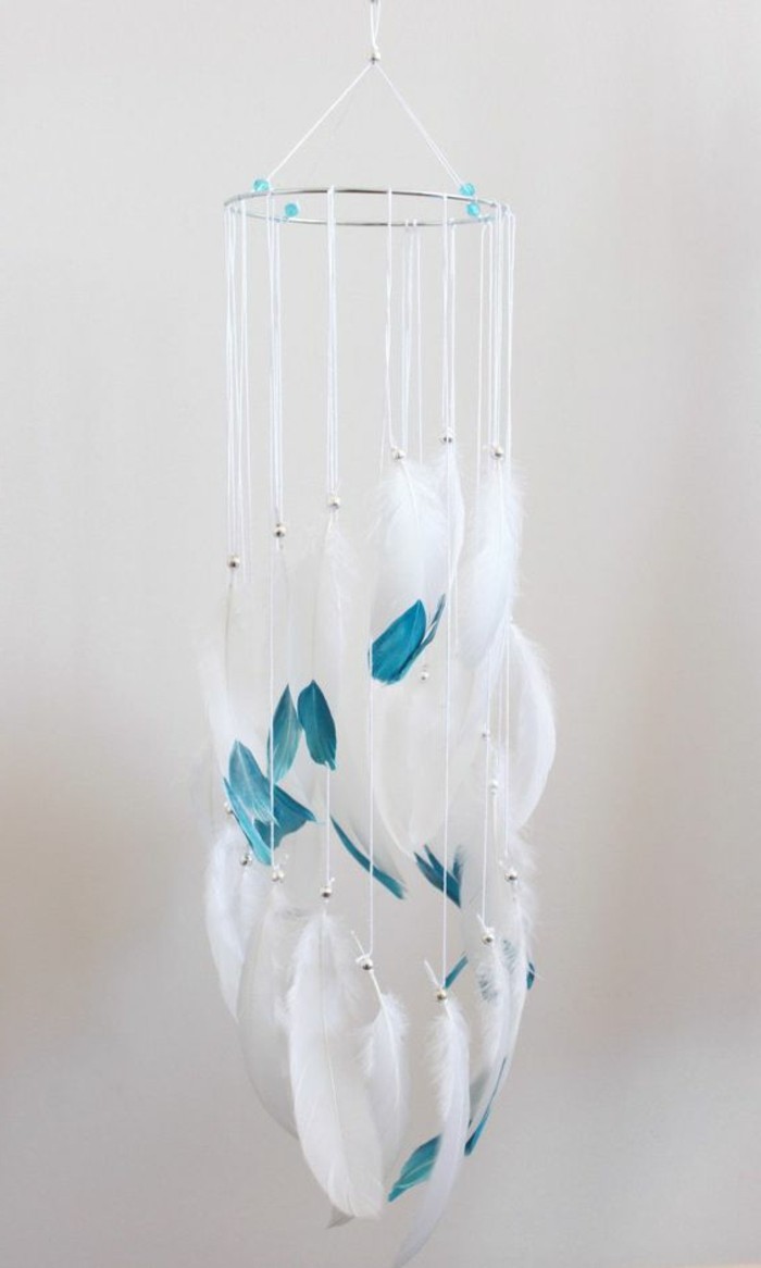feathers in white, with teal tips, tied to a mobile-style dreamcatcher in white, hanging from the ceiling