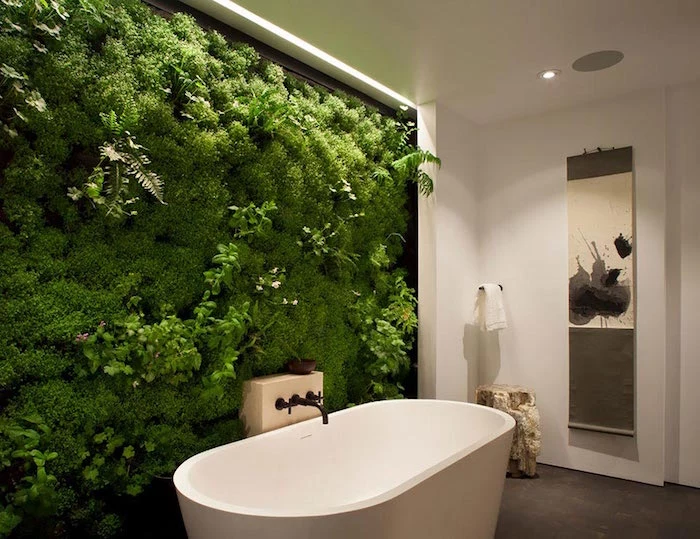 ferns and moss, and other green plants, entirely covering a wall, near a white round bathtub, nice bathrooms, the rest of the walls are white, and the floor is beige