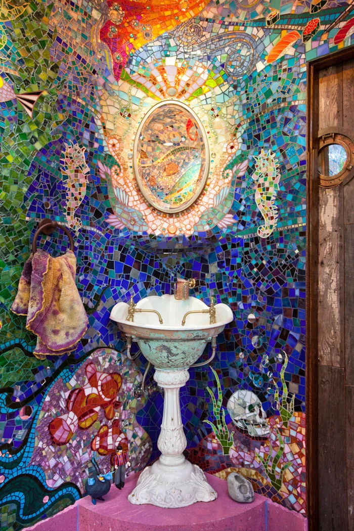 mosaic in many different colours, with fish and other sea creatures, bathroom wall decor ideas, antique style sink, pink floor and a wooden door