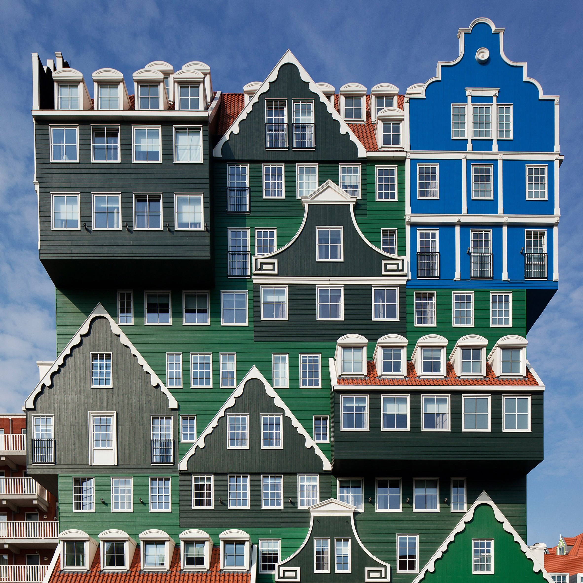 mix of different styles, on a building in blue, green and grey, with orange tiled roof details, and white decorative elements, postmodern architecture, gabled roofs and georgian windows