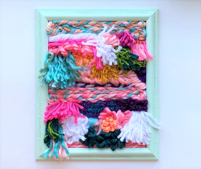 diy gifts for friends, colorful yarn in different shapes, inside a wooden turquoise frame, mounted on white wall