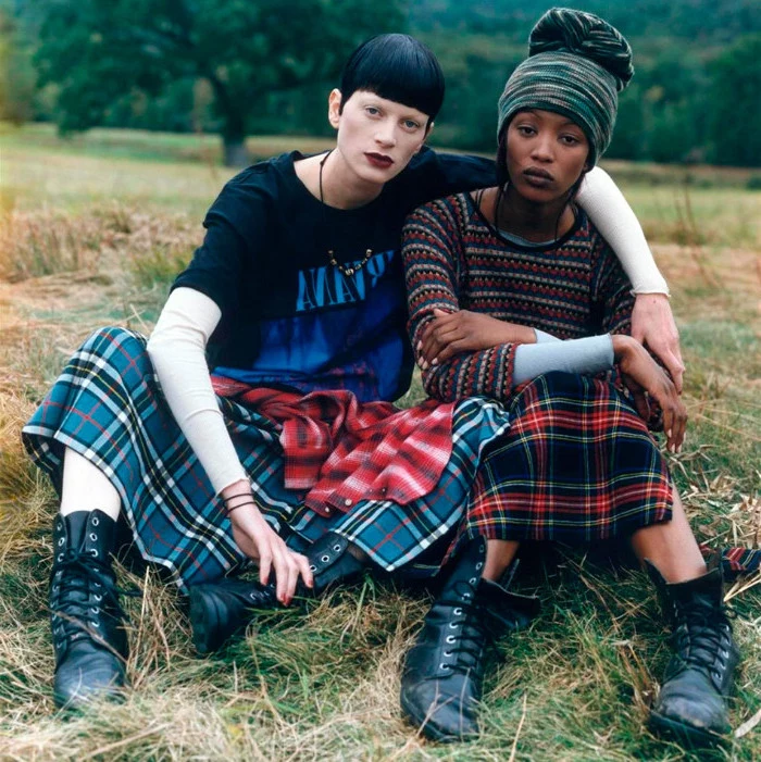 models dressed in retro outfits, sitting on a grassy area, 90s clothes womens, lace up ankle boots, tartan skirts and colorful tops