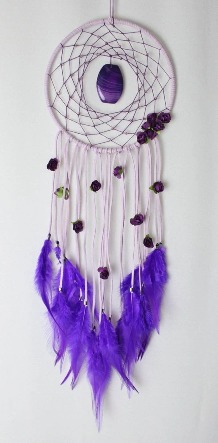 stine in purple, decorating a pale purple dreamcatcher, with long tassels, and neon violet feathers
