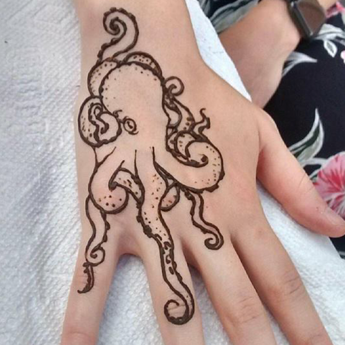 funny drawing of an octopus, done with dark brown henna, on a pale hand, with outstretched fingers