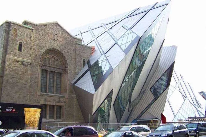 jagged glass and metal structure, fused with an old building, made from beige bricks or stone, and featuring ornate widnows