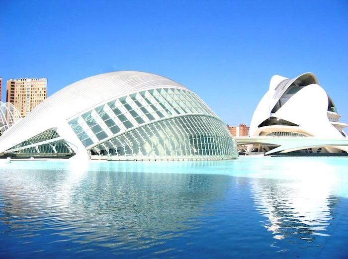 cultural center in valencia spain, with an oval shape and metal bar-like structures, post modernity, built on a blue pool of water