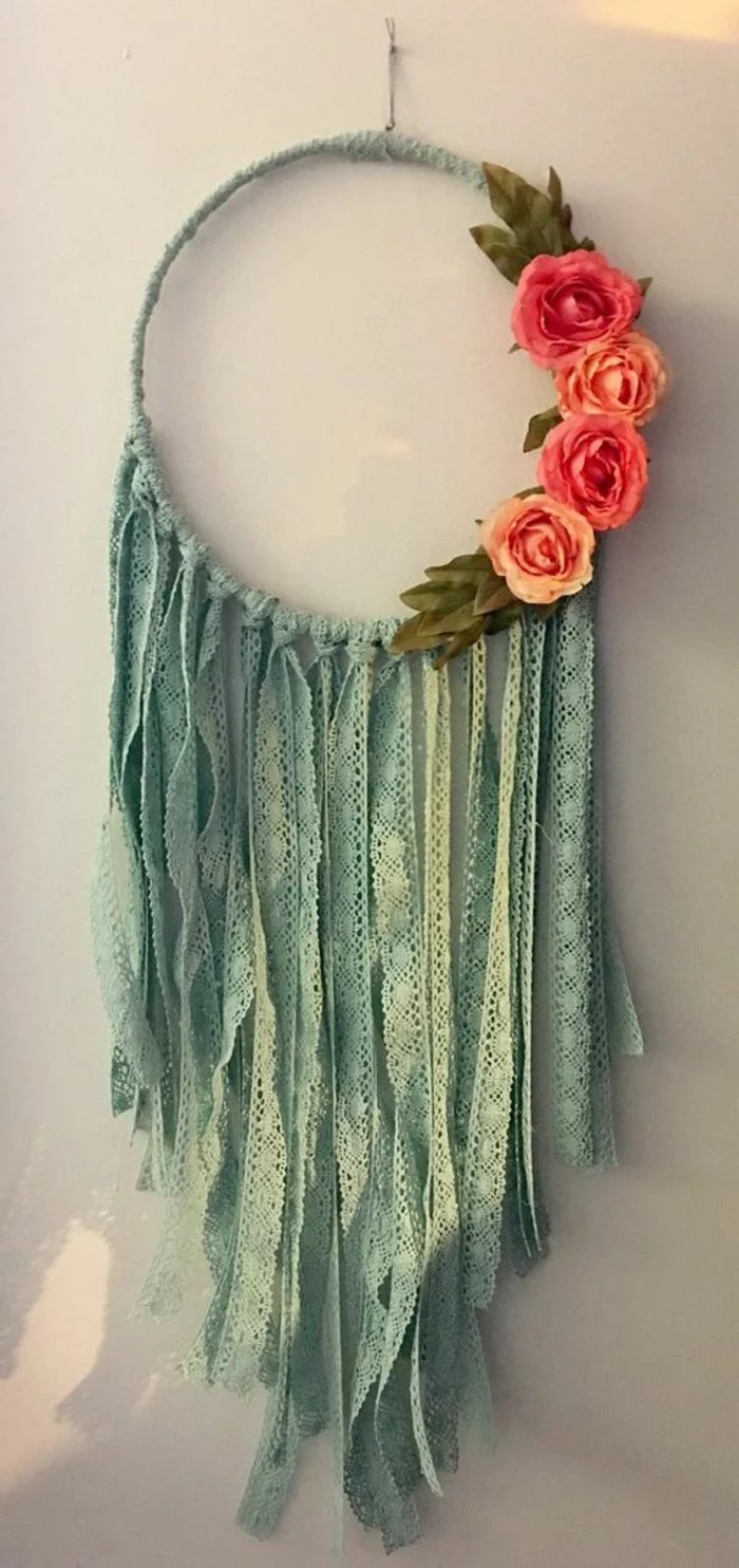 hoop wrapped in pale teal leather rope, decorated with many strips of teal lace, big dream catchers, four orange faux roses on its left side
