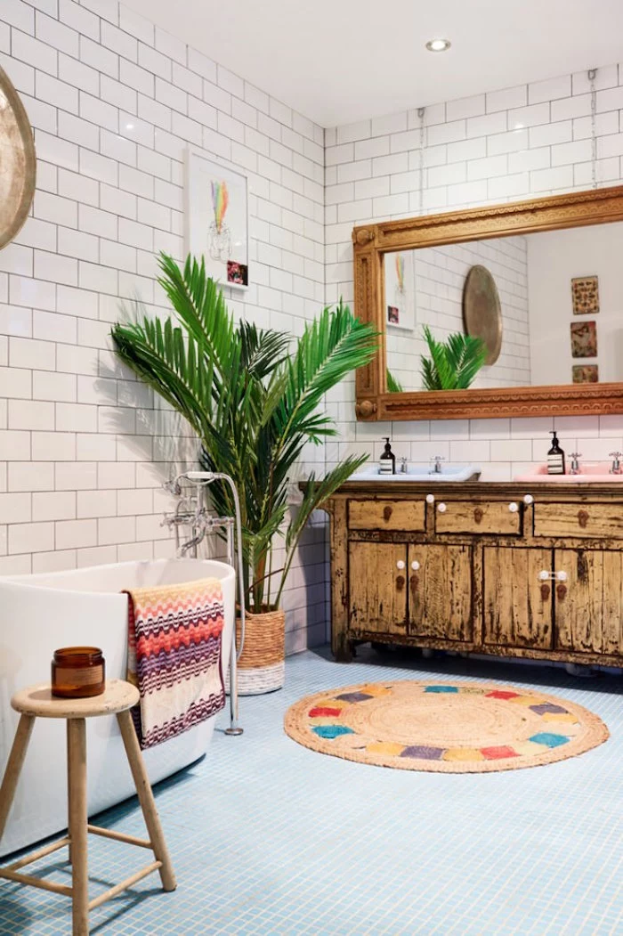 shabby chic cupboard in pale brown, a large mirror in a wooden frame, and a potted palm tree, bathroom decorating ideas on a budget, round multicolored rug
