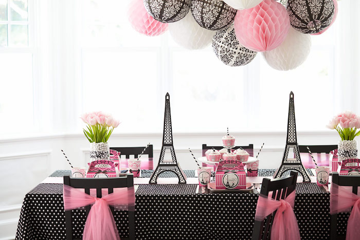 pink and black table setup, decorated with eiffel tower figurines, and two bouquets of pale pink flowers, 60th birthday color, parisian party theme