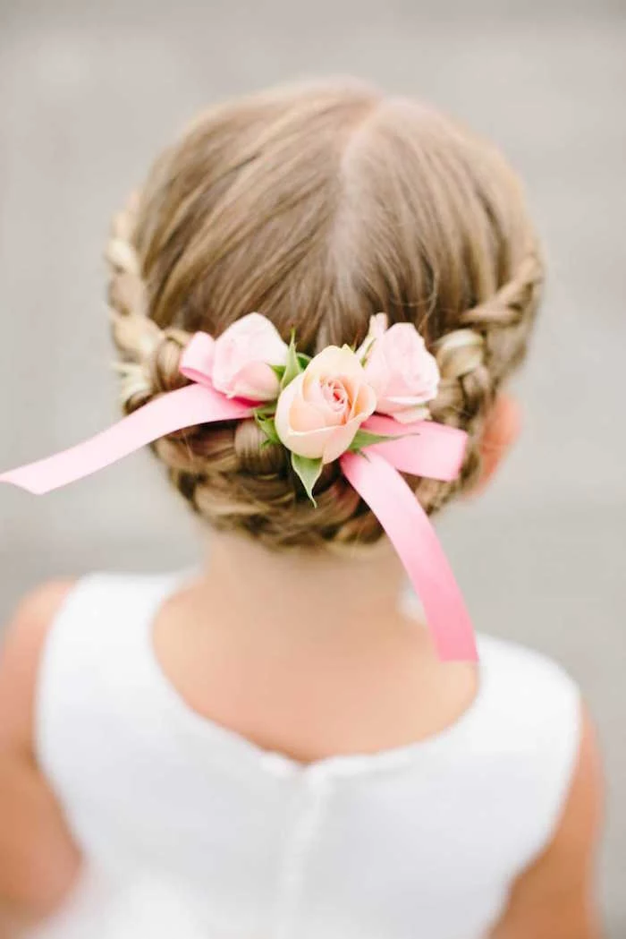 bridesmaid or flower girl's hairstyle, seen from the back, dark blonde hair, with a braided up-do, decorated with pale, peach-colored roses, and a pink ribbon