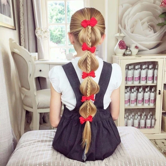 five small red bows, decorating the long, blonde hair of a young girl, with a weist-long braid, simple hairstyles, dark grey pinafore dress, with a white short-sleeved shirt