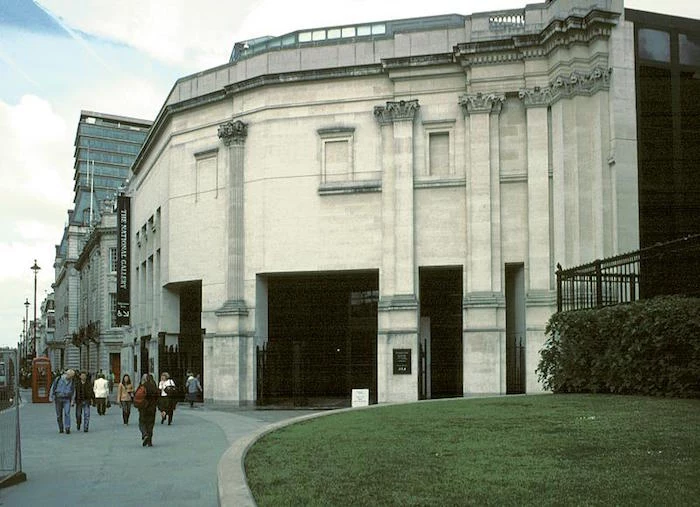 off-white and grey concrete building, with filled-in windows, and roman-like columns, sainsbury wing of the national gallery in london, next to a busy street
