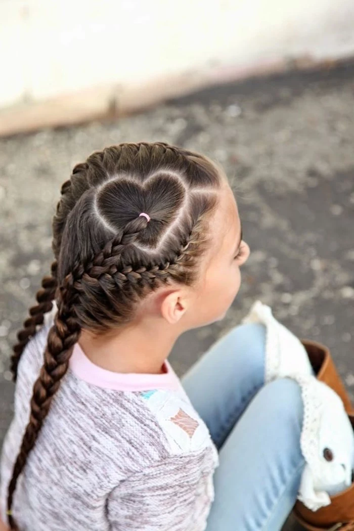 sitting young girl, dressed in pale jeans, and a multicolored jumper, with dark brunette hair, woven into several braids, kids hairstyles, forming a heart pattern on top of her head