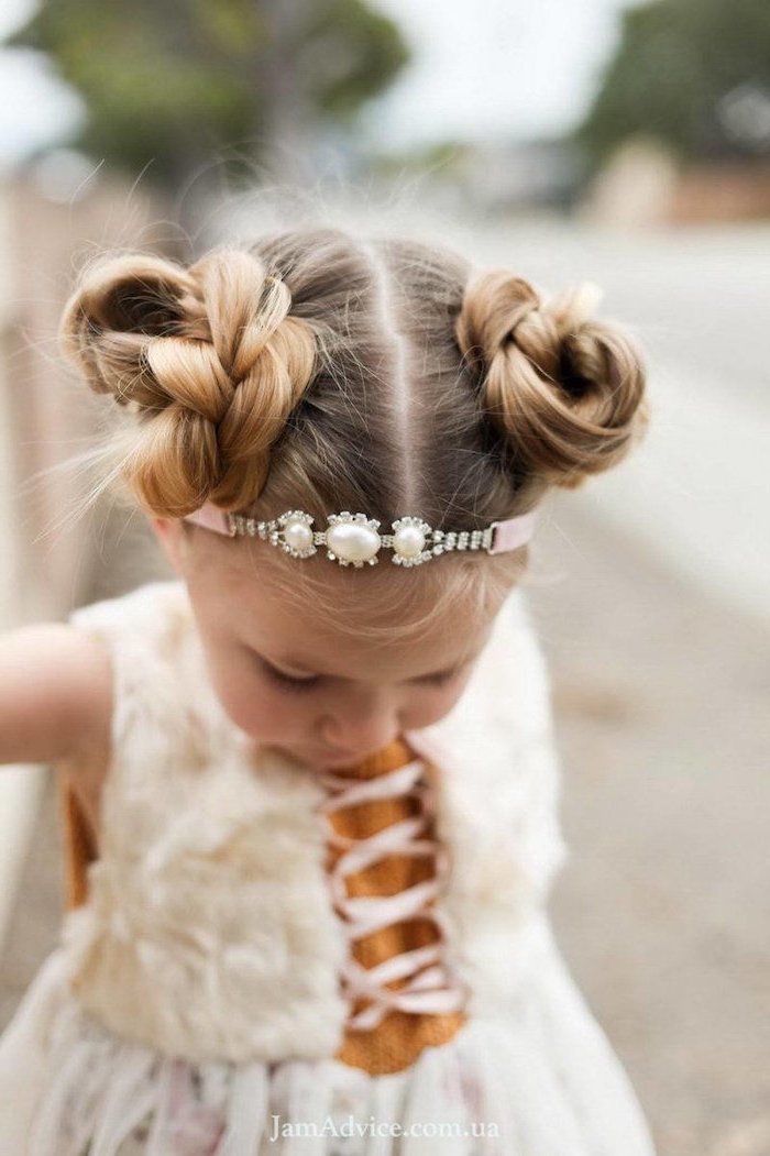 headband in pink, decorated with diamante, and pearl-like stones, on the head of a small blonde child, with two braided buns, little girl haircuts