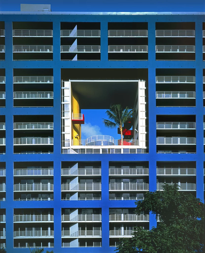 blue rectangular building, with a hollow square in the middle, containing elements in yellow, red and white, and a palm tree, atlantis condominium, postmodern architecture, lots of terraces with white railings