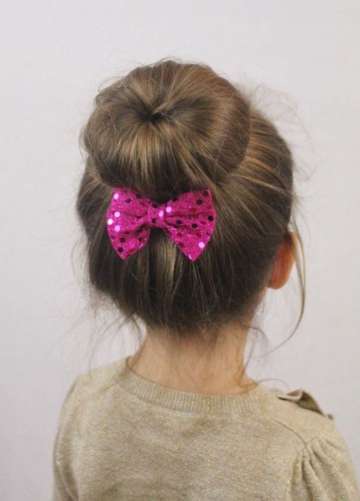 donut bun with a sparkly, sequined fuchsia pink bow, on the brunette head of a child, simple hairstyles 