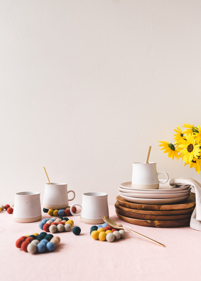 set of ceramic mugs and wooden plates, homemade christmas gifts, coasters made out of colorful pompoms