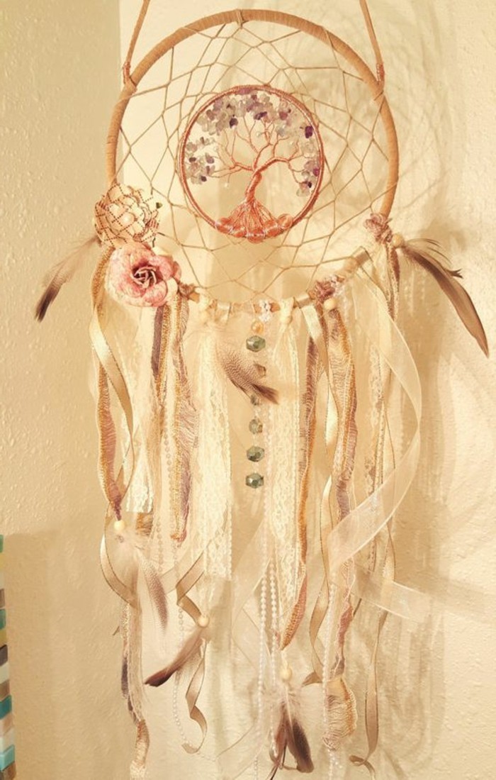 the tree of life, decorating the middle, of a beige and cream dreamcatcher, decorated with sheer white ribbons, feathers and a flower, and many beads, pictures of dream catchers