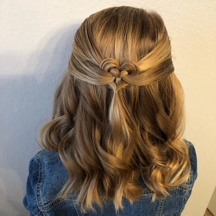 denim jacket worn by young girl, with dark blonde, shoulder-length wavy hair, decorated with a heart-shaped braid detail, little girl haircuts, natural hair highlights