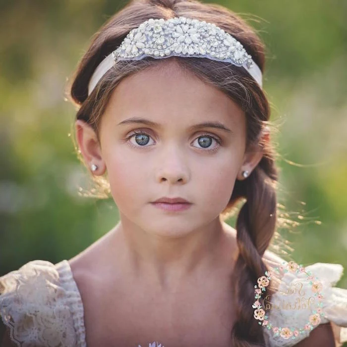 bejeweled white headband, with pearl-like details, on the head of a young child, with brunette hair, tied into a side braid, falling over her shoulder, cute hairstyles