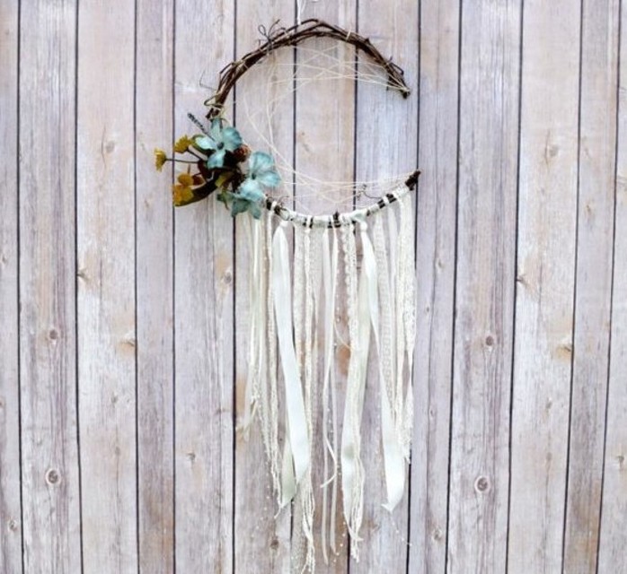 wooden fence or wall, decorated with a crescent moon dreamcatcher, pictures of dream catchers, with cream lace ribbon tassels, and pale blue flower ornaments