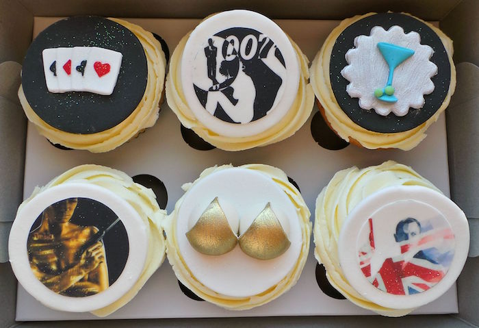 playing cards and cocktail glass, gold bra and images from the bond movies, topping a set of six cupcakes