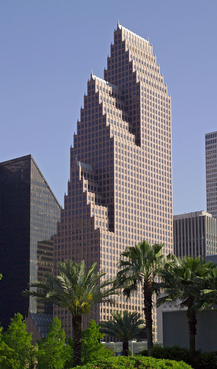 palm trees and other foliage, in front of a large skyscraper, composed of three layers, each ending in a terraced roof, modernism and postmodernism, lots of square windows