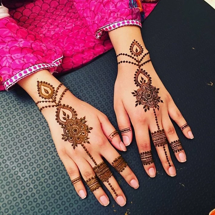 identical henna tattoo designs, on the hands of a woman, dressed in a fuchsia pink sari