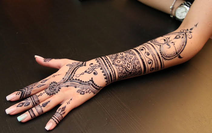 henna meaning, hearts and flowers, flourishes and various symmetrical motifs, decorating the hand and forearm, of an outstretched arm