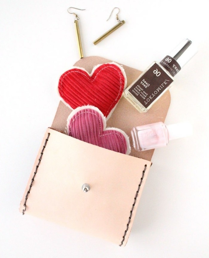cute birthday ideas, cream leather purse, opened to reveal two bottles of nail polish, two fabric heart ornaments, in red and pink, and a pair of gold earrings