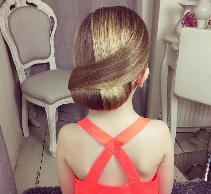 wrap-over style up-do, on blonde hair, with natural highlights, worn by a small girl, in a coral red formal dress