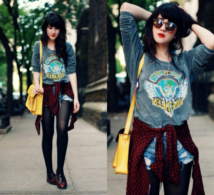 messenger bag in yellow, worn by a dark-haired woman, with a long-sleeved grey printed tee, ripped denim shorts, black tights and a red flannel shirt