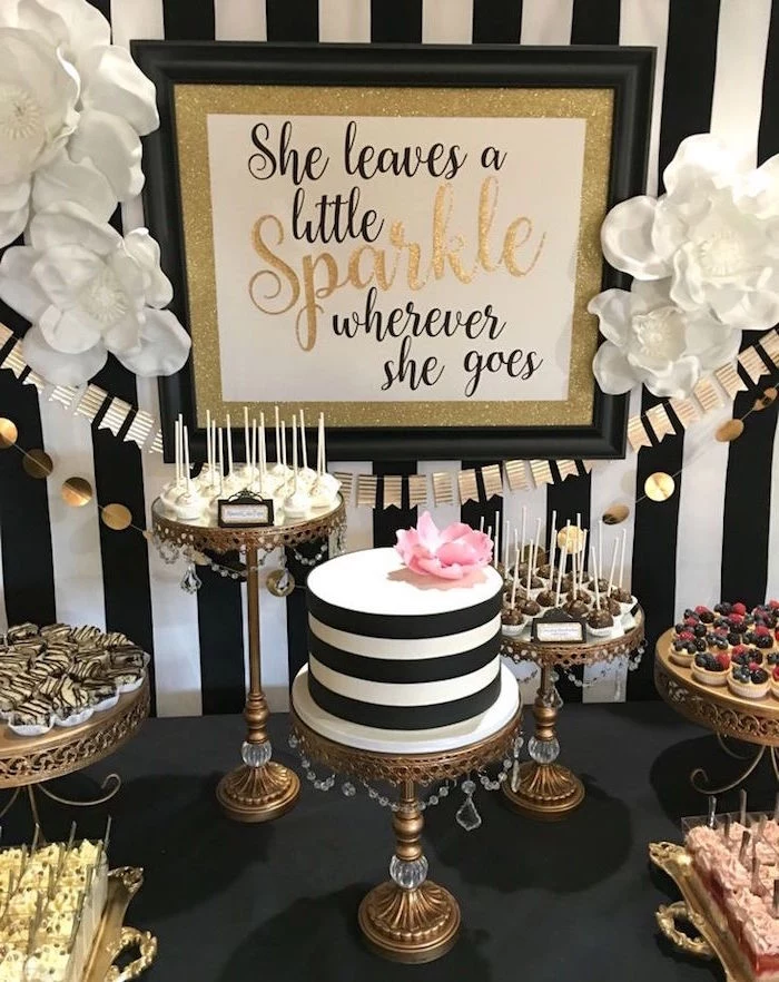 tartlets and cake pops, and various other sweets, near a striped black and white cake, topped with a pink flower, 60th birthday party ideas for mom, black white and gold poster, with a festive message