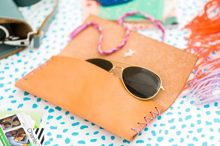 leather sunglasses pouch with pink stitching, sunglasses inside, thoughtful christmas gifts, blue and white surface