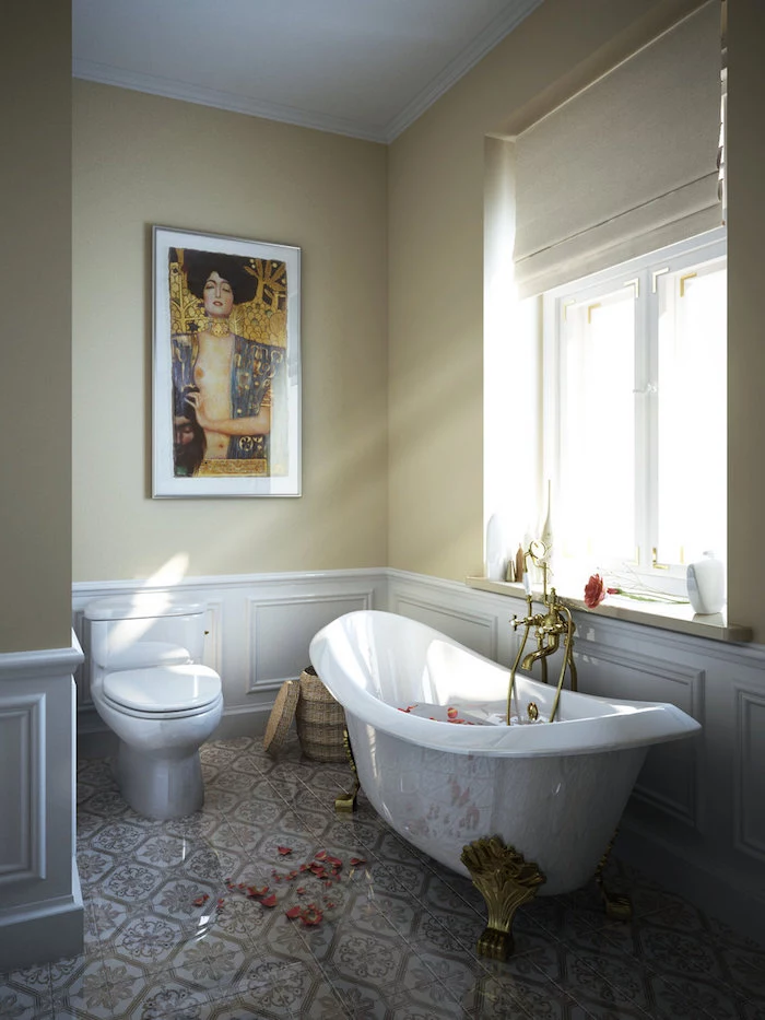 klimt artwork print, framed on the pale yellow wall, of a sunlit room, with white panelling, beige and white tiles on the floor, and a window, bathroom wall decor ideas, claw-footed antique white bathtub, and the matching toilet bowl