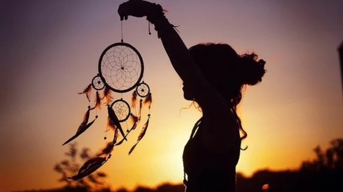 diy dreamcatcher, a woman's silhouette, holding a dreamcatcher, with a yellow, orange and purple sunset in the background