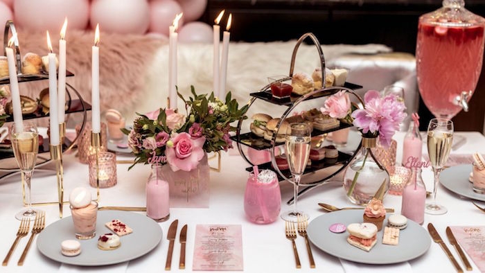 high tea table set up, with finger foods, macarons and various other desserts, 60th birthday party ideas for mom, pink and white theme, with flowers and candles 