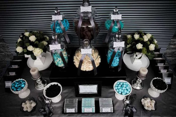 grey and teal snacks table, with a selection of vintage sweets in jars, and two bouquets of white roses, 60th birthday color 