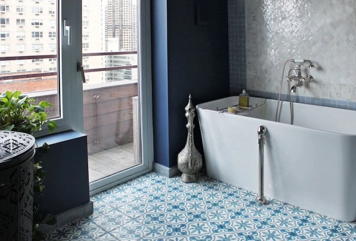 smooth modern bathtub in white, inside a room with a terrace, and blue and white tiles on the floor