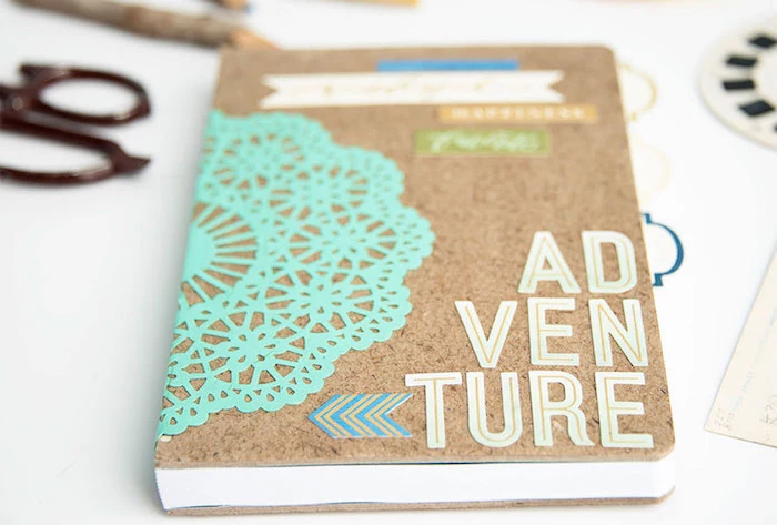 travel journal with the word adventure written at the front, creative homemade gifts, placed on white table