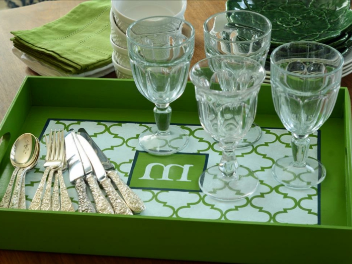 cutlery and four glasses, on a green monogrammed serving tray, decorated with a symmetrical pattern