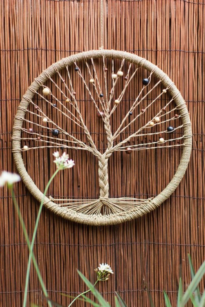 round decoration with a tree of life motif, woven with string, and decorated with beads, large dream catcher like ornament, on a rattan background