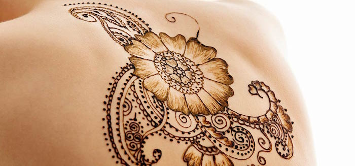 back tattoo of a flower, with paisleys and flourishes, painted with henna, henna meaning, seen in close up