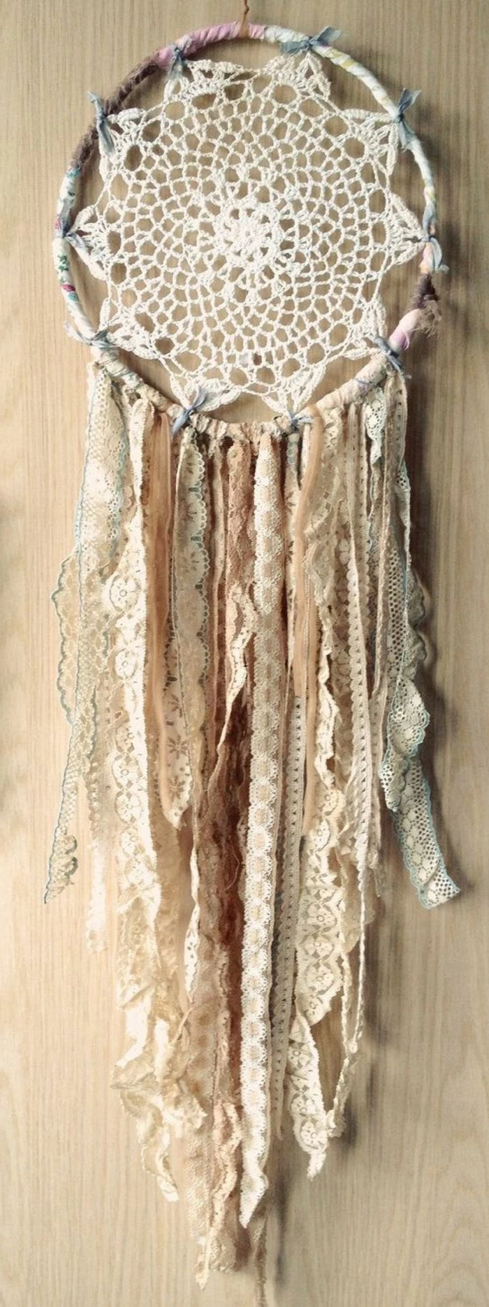 antique lace ribbons, in pale beige, cream and off white, attached to a boho dreamcatcher, with a crocheted doily, pictures of dream catchers, pale beige wooden background 