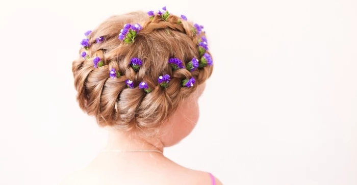 blossoms in violet, decorating the braided head, of a dark blonde child, little girl hairstyles, seen from the back
