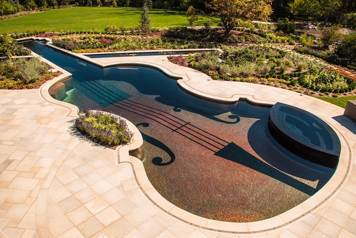 flowers planted in patterns, near a pool shaped like a violin, surrounded by pale cream tiles, backyards with pools