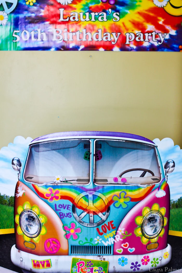 cardboard cutout of a hippie van, decorated with multicolored flowers, peace signs and graffiti, tie-dye effect birthday banner