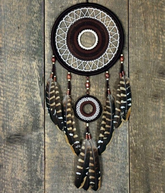 dark brown and black diy dreamcatcher, with a white net, decorated with striped feathers, and brown and black beads